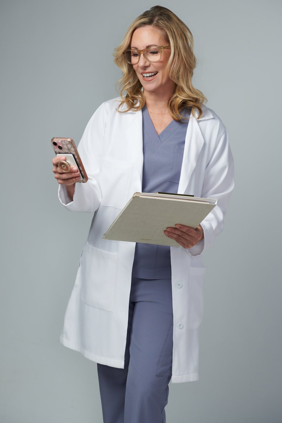 Dr. Stephanie Moore in a white coat and scrubs holding a tablet